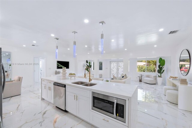 kitchen featuring visible vents, open floor plan, marble finish floor, stainless steel appliances, and a sink