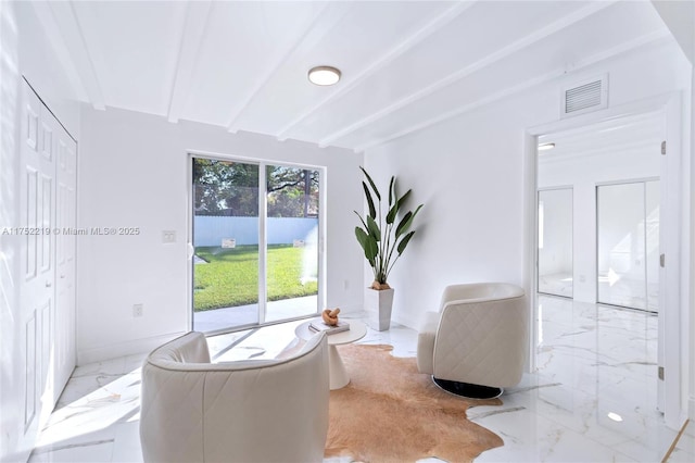 sitting room with marble finish floor, baseboards, visible vents, and beam ceiling