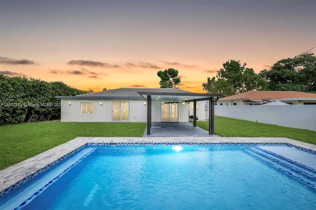 rear view of house with a yard, a patio, fence, and a fenced in pool