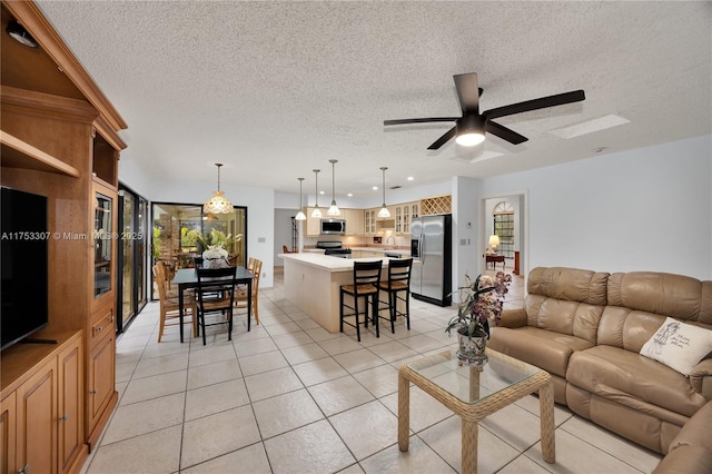 living area featuring light tile patterned floors, ceiling fan, and a textured ceiling