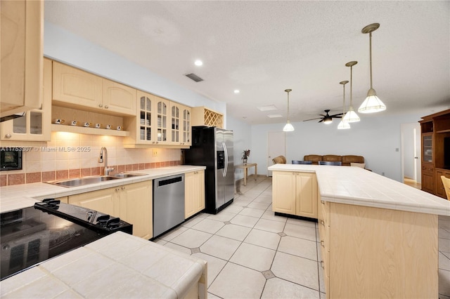 kitchen featuring tile counters, tasteful backsplash, visible vents, appliances with stainless steel finishes, and a sink