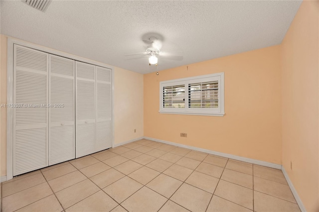 unfurnished bedroom featuring light tile patterned floors, a closet, a textured ceiling, and visible vents