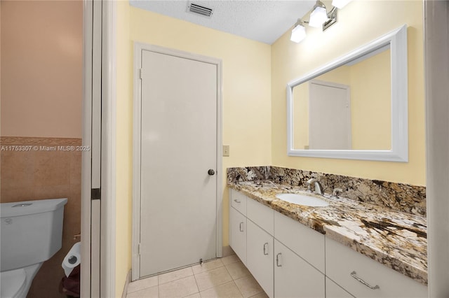 bathroom with tile walls, visible vents, a textured ceiling, vanity, and tile patterned flooring