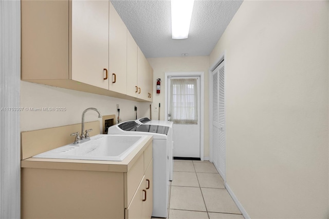 laundry area with light tile patterned floors, cabinet space, washer and dryer, a textured ceiling, and a sink