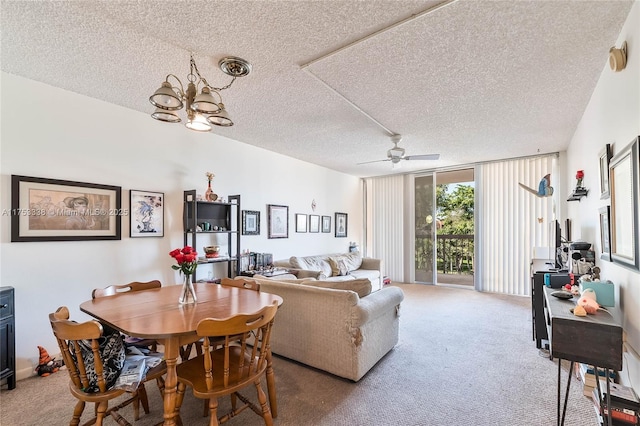 carpeted dining space with floor to ceiling windows, a textured ceiling, and ceiling fan with notable chandelier