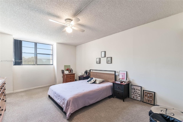 bedroom featuring light carpet, a textured ceiling, baseboards, and a ceiling fan