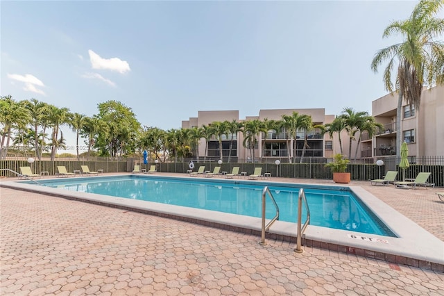 community pool with a patio area and fence