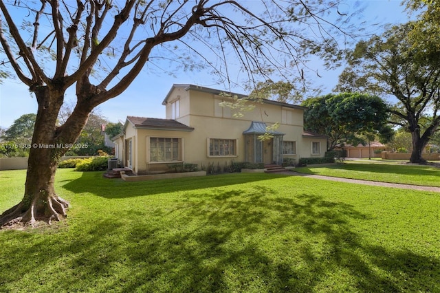 view of front of home with a front lawn, central AC unit, fence, and stucco siding