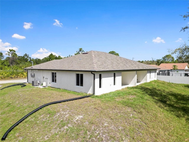 back of house with central AC, a shingled roof, fence, a yard, and stucco siding