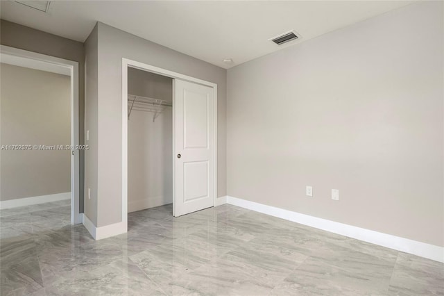 unfurnished bedroom with marble finish floor, a closet, visible vents, and baseboards