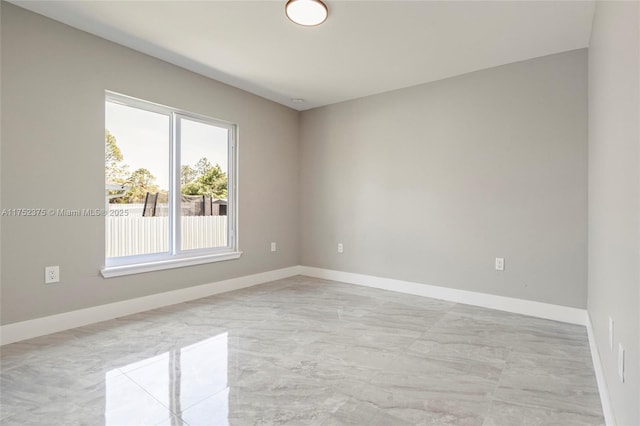 unfurnished room with marble finish floor and baseboards