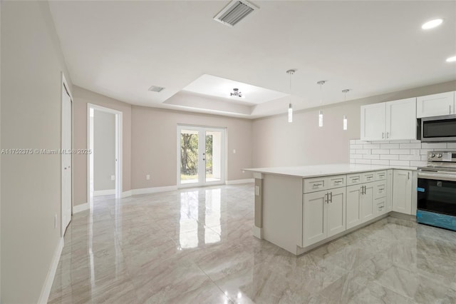 kitchen with marble finish floor, appliances with stainless steel finishes, a tray ceiling, and french doors