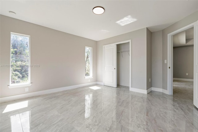 unfurnished bedroom with marble finish floor, multiple windows, and baseboards