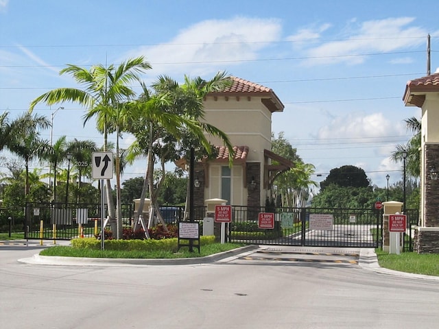 view of street with traffic signs, a gate, curbs, and a gated entry