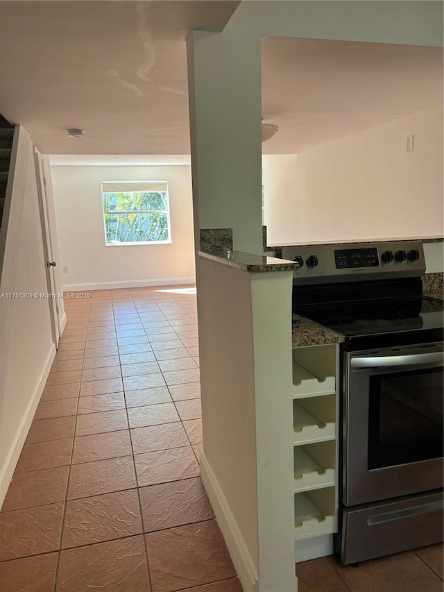 kitchen with stainless steel range with electric stovetop, stone countertops, baseboards, and tile patterned floors