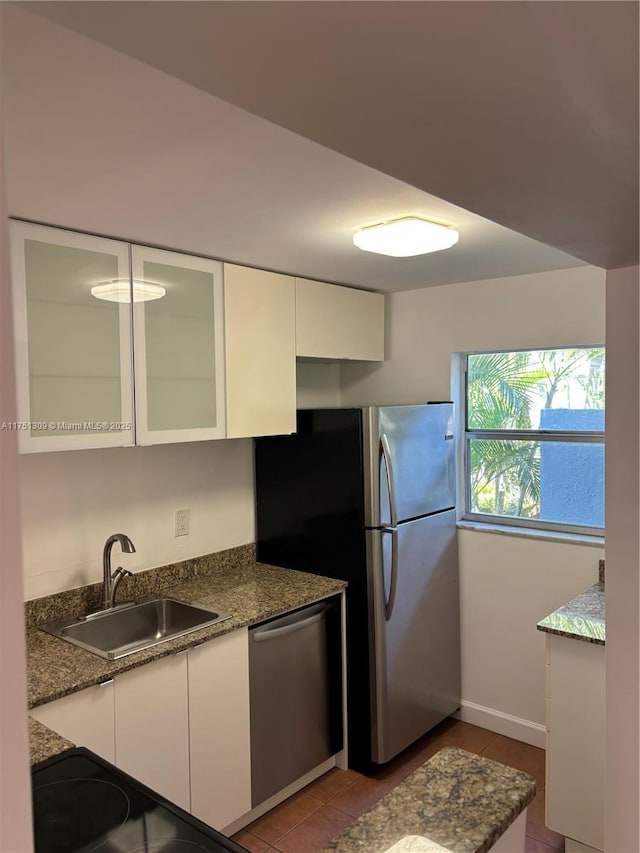 kitchen with stainless steel appliances, glass insert cabinets, white cabinets, a sink, and tile patterned floors