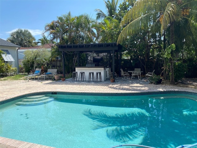 view of swimming pool with a patio area, fence, outdoor dry bar, and a fenced in pool