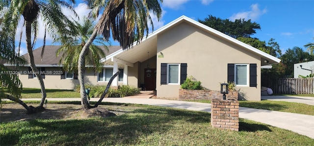 view of front of home featuring a front lawn, fence, and stucco siding