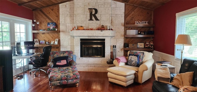 living area featuring wooden ceiling, vaulted ceiling, and a stone fireplace