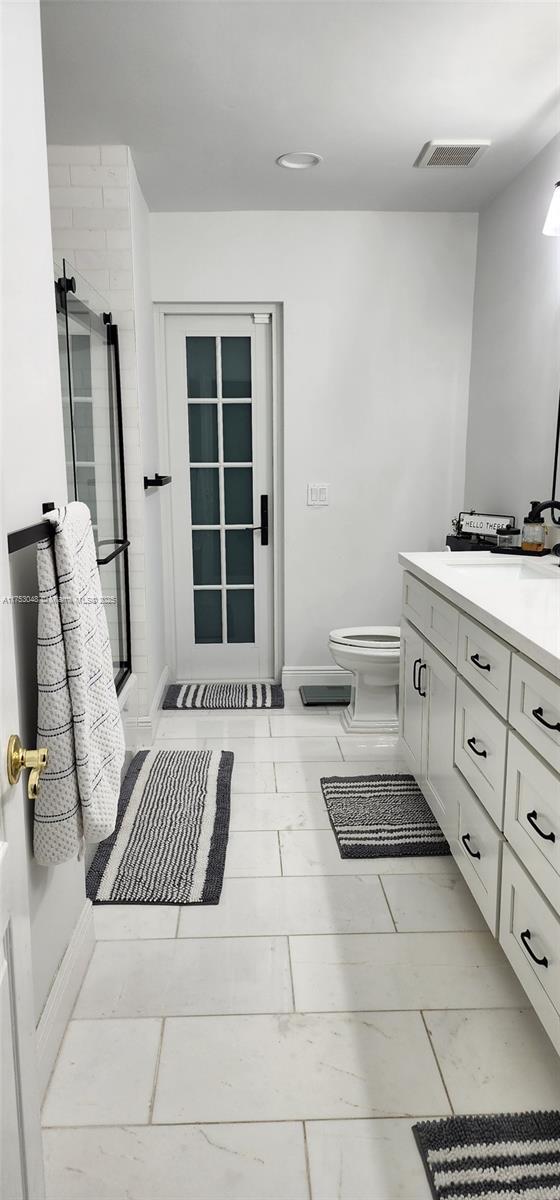 full bathroom with visible vents, toilet, a shower stall, vanity, and baseboards