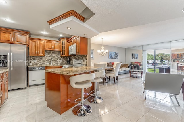 kitchen with a breakfast bar, backsplash, brown cabinetry, open floor plan, and white appliances