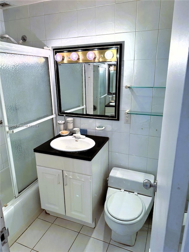 full bathroom with toilet, vanity, tile walls, and tile patterned floors