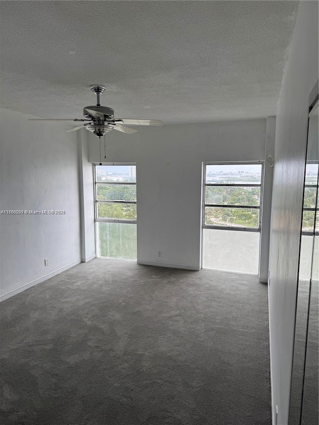 carpeted spare room featuring a textured ceiling and ceiling fan