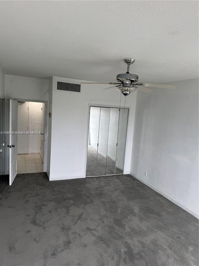 unfurnished bedroom featuring a textured ceiling, a closet, carpet, and visible vents