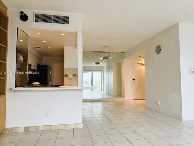 kitchen featuring visible vents, light tile patterned flooring, and freestanding refrigerator