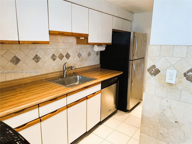 kitchen with light tile patterned floors, light countertops, appliances with stainless steel finishes, white cabinetry, and a sink