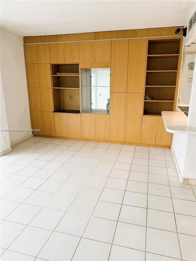 spare room featuring wood walls, built in shelves, and light tile patterned floors