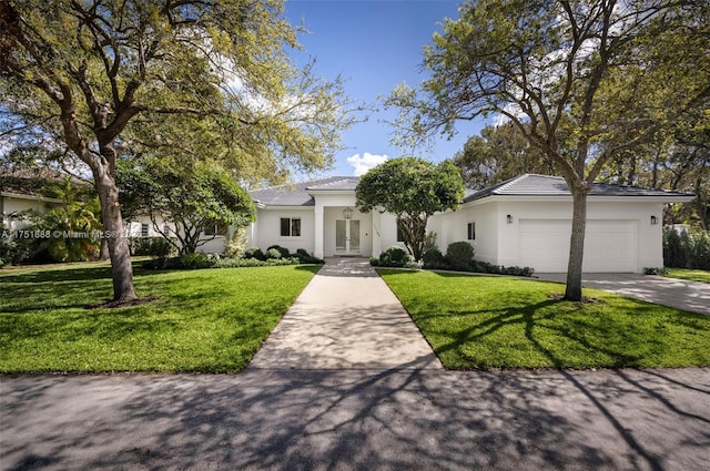 view of front of home with a front lawn, driveway, an attached garage, and stucco siding