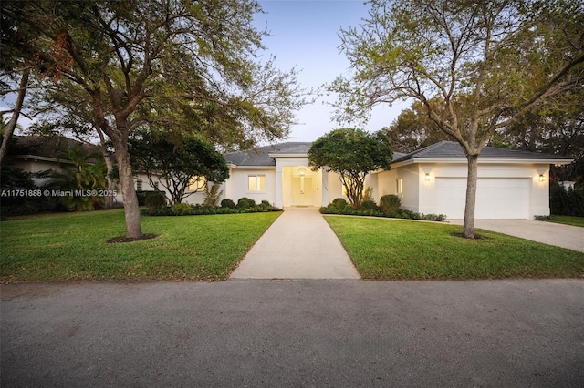 ranch-style house with a garage, a front lawn, concrete driveway, and stucco siding