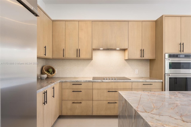 kitchen with light stone counters, stainless steel double oven, light brown cabinets, and black electric stovetop