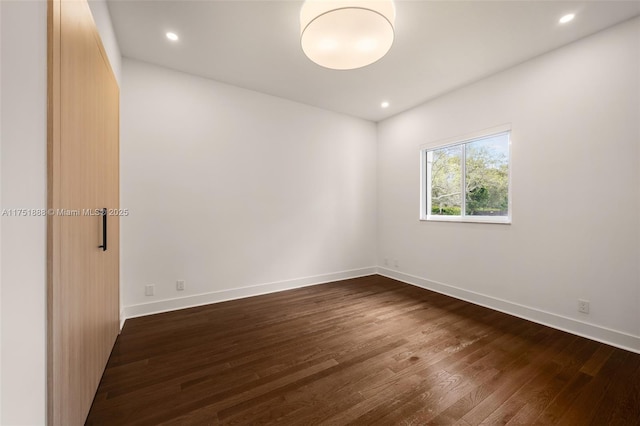 empty room with baseboards, dark wood-style flooring, and recessed lighting