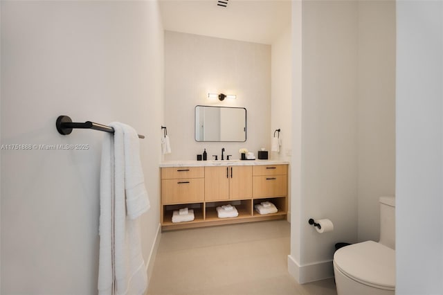 bathroom featuring toilet, baseboards, and vanity