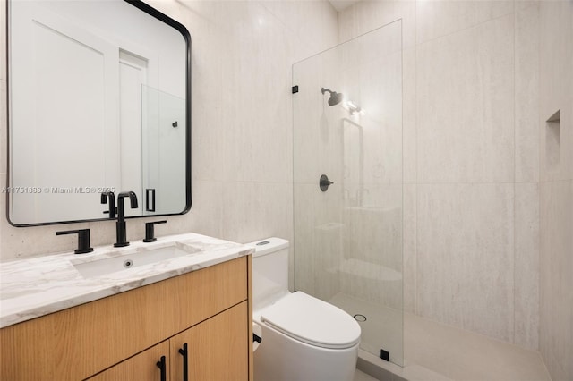 full bathroom with tiled shower, tile walls, toilet, and vanity