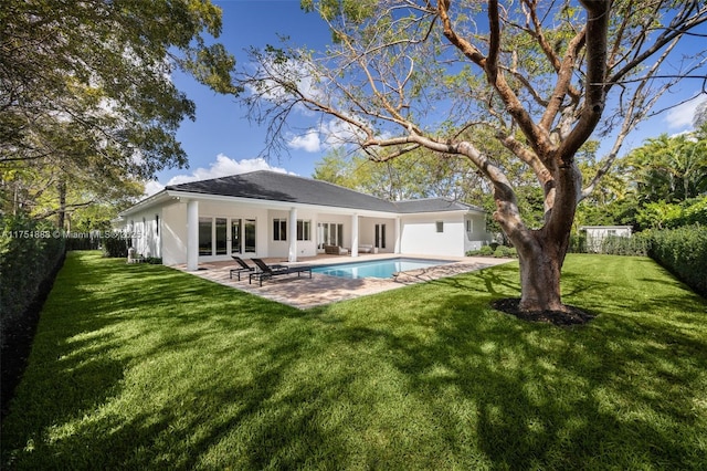 back of property with a fenced backyard, an outdoor pool, a lawn, stucco siding, and a patio area