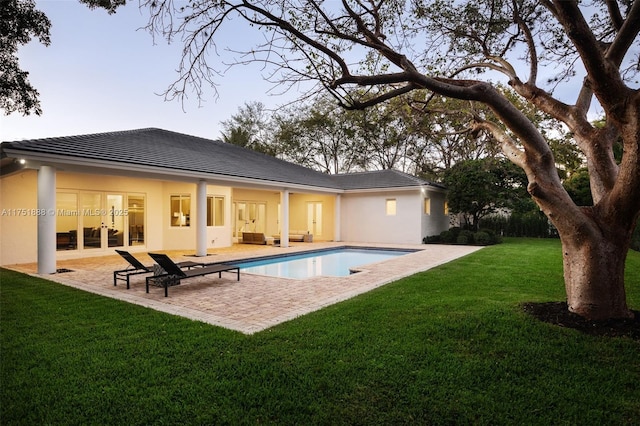 rear view of house featuring a patio area, a lawn, and stucco siding