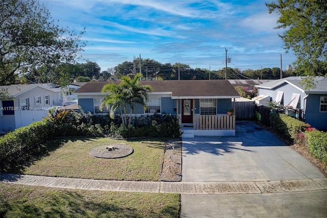 ranch-style house with a front yard, driveway, and fence