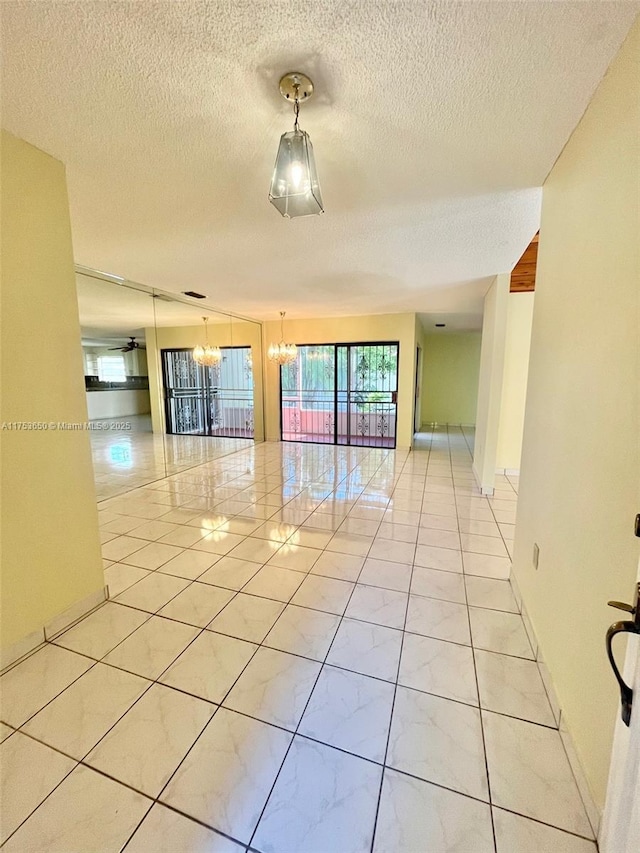 spare room with baseboards, a chandelier, a textured ceiling, and light tile patterned flooring