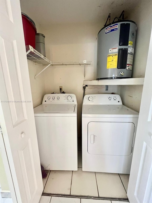 laundry room featuring light tile patterned floors, laundry area, washing machine and clothes dryer, and electric water heater