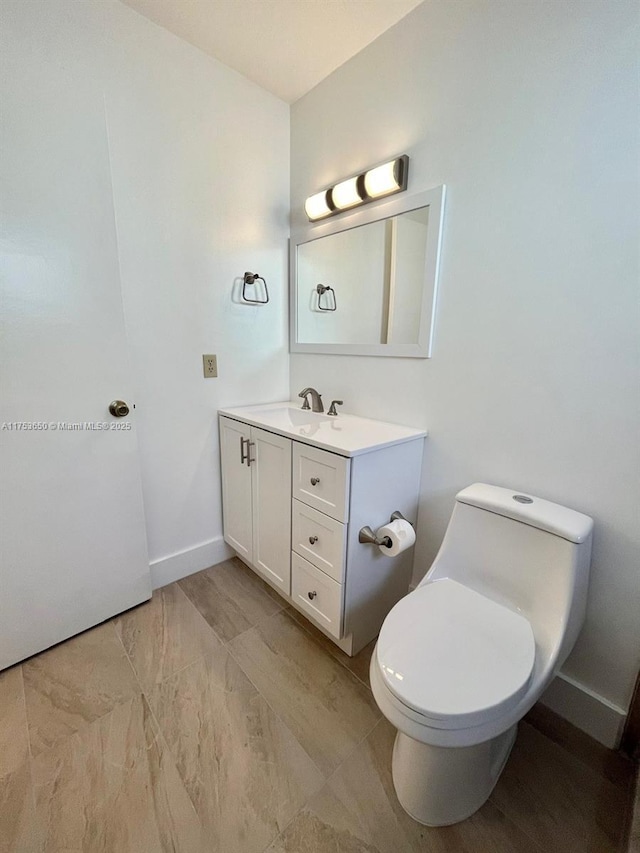 bathroom with toilet, baseboards, and vanity