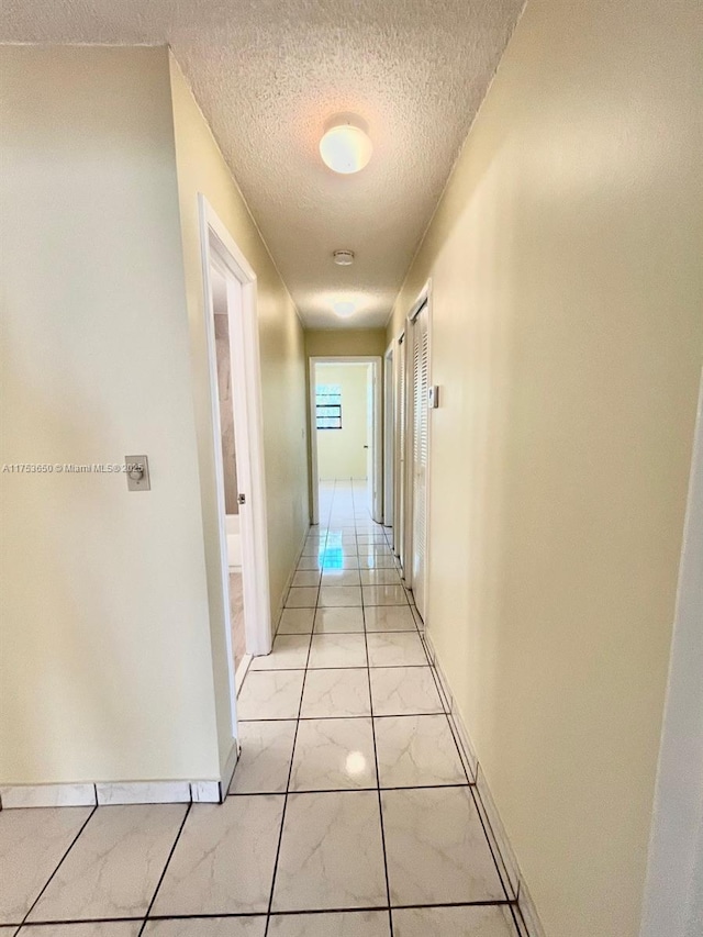 corridor featuring a textured ceiling and baseboards