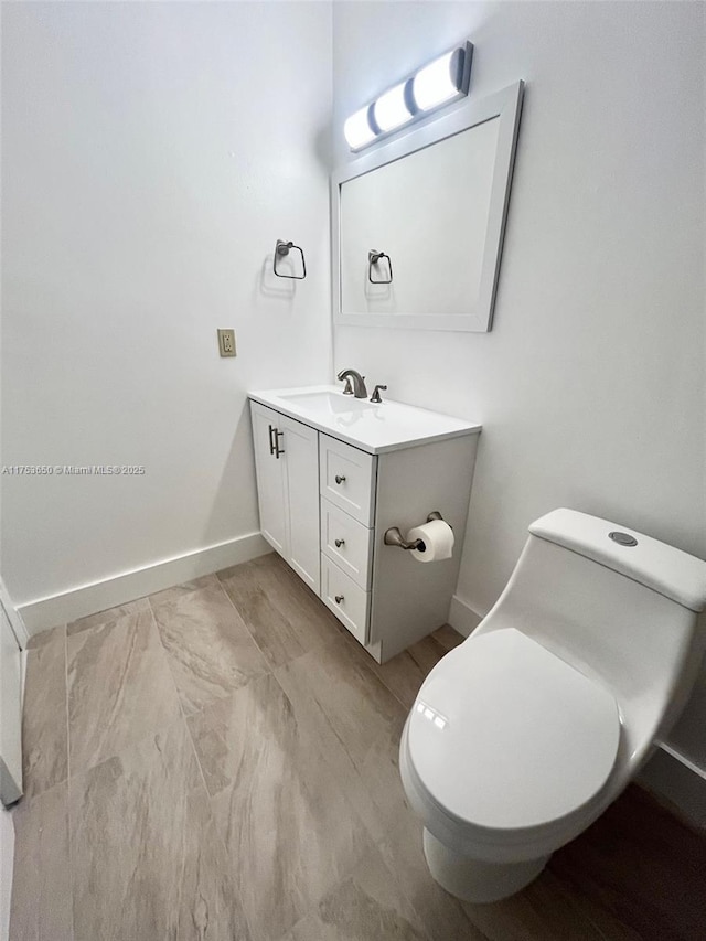 bathroom featuring toilet, vanity, and baseboards