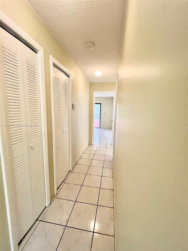 hall with light tile patterned floors and a textured ceiling