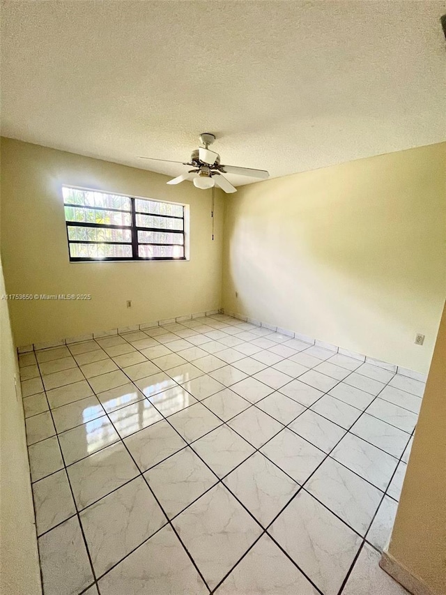 spare room with ceiling fan, a textured ceiling, and tile patterned flooring