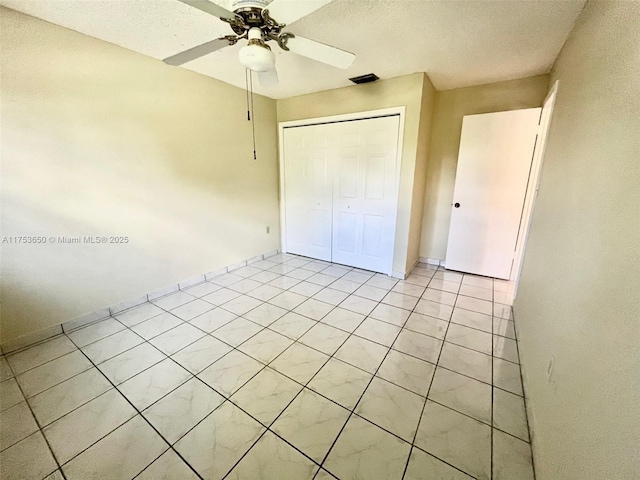 unfurnished bedroom featuring light tile patterned floors, a closet, visible vents, ceiling fan, and a textured ceiling