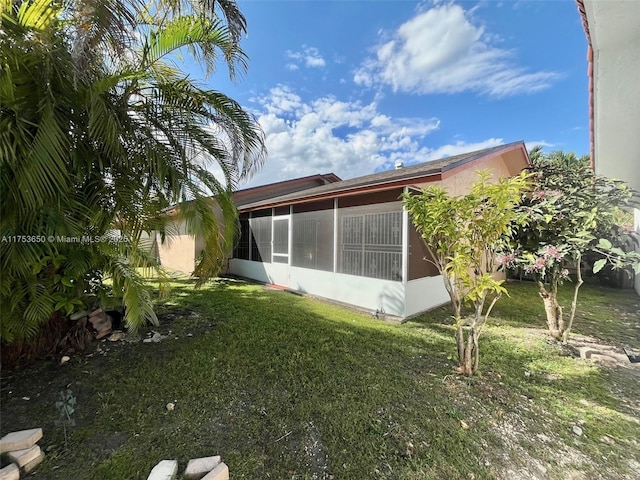 rear view of property with a sunroom and a yard