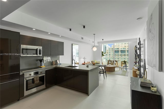 kitchen with recessed lighting, stainless steel appliances, a peninsula, a sink, and modern cabinets